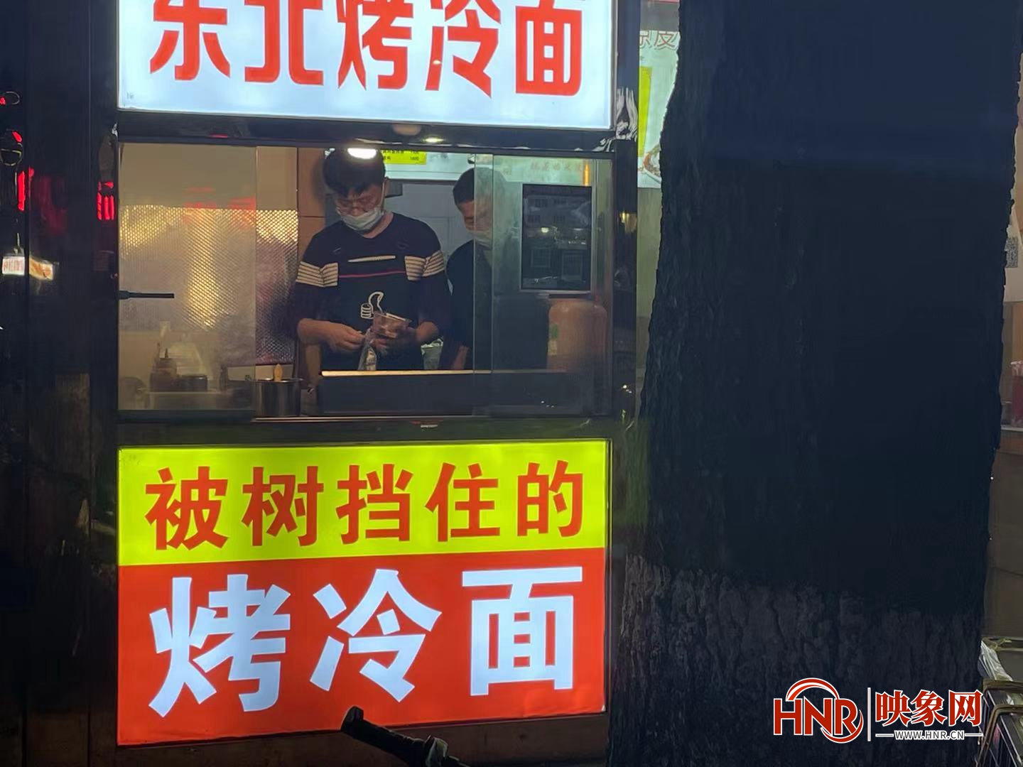 郑州一小吃摊被树挡住 店主干脆起名“被树挡住的烤冷面”