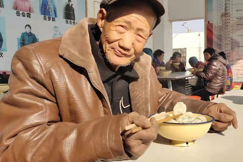 伊川县平等乡上元村老人暖阳下吃饺子翘拇指感党恩