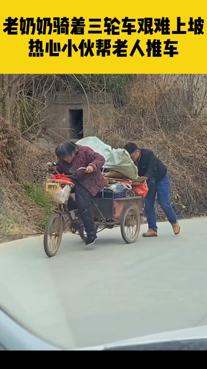 老奶奶骑着三轮车艰难上坡热心小伙帮老人推车